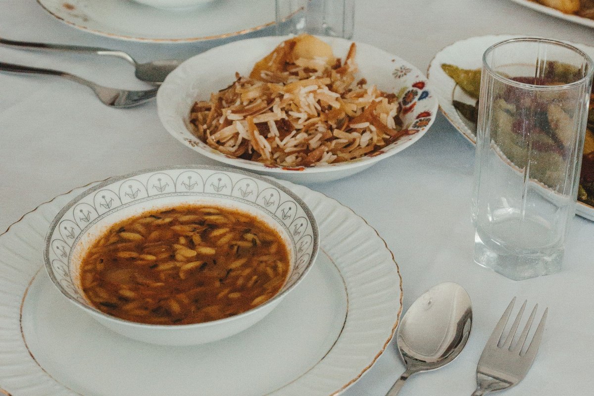 Table set with a bowl of soup, rice with vegetables, bread and cutlery
