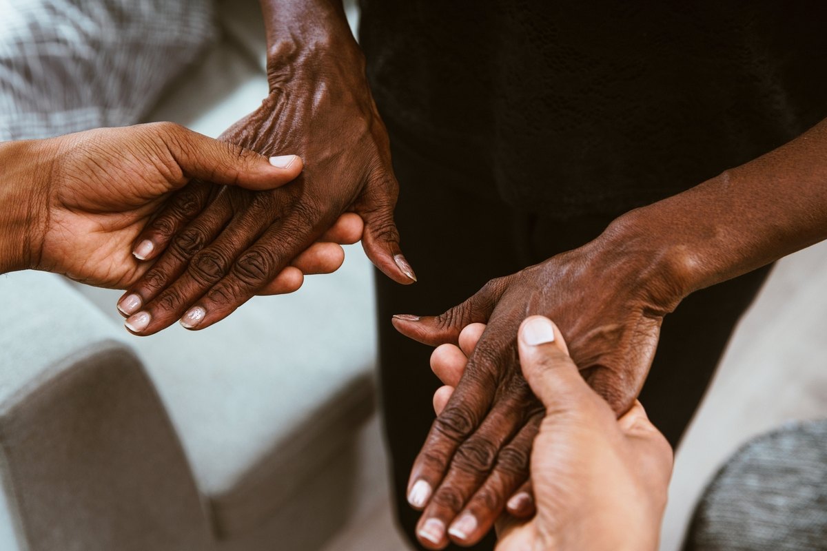 Younger hands gently holding the wrinkled hands of an older person