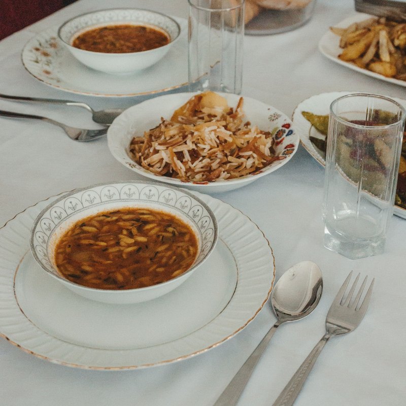 Table set with a bowl of soup, rice with vegetables, bread and cutlery
